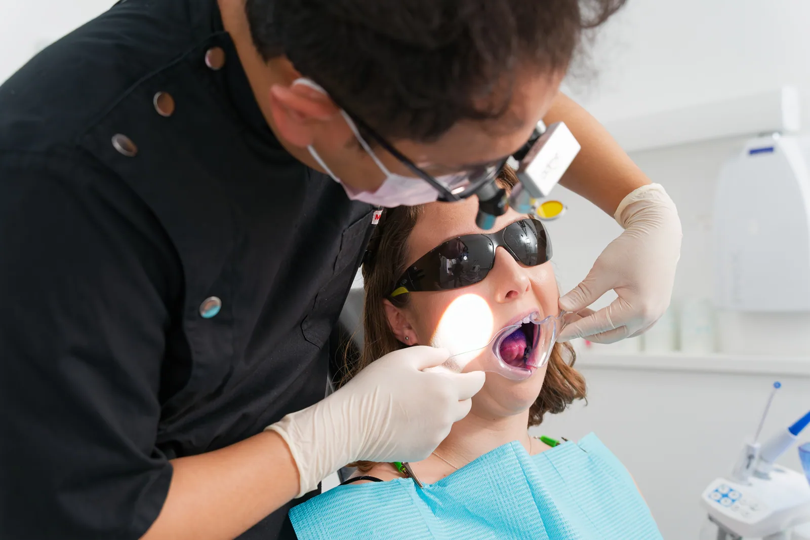 Dentist using a cheek retractor and light to examine a patient's mouth at the clinic