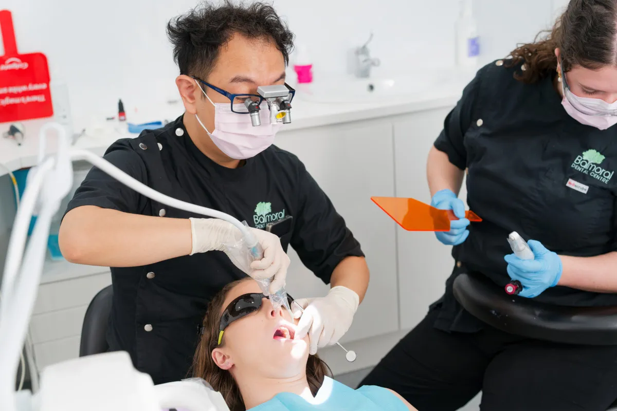 Clinicians placing a dental implant under local anaesthetic